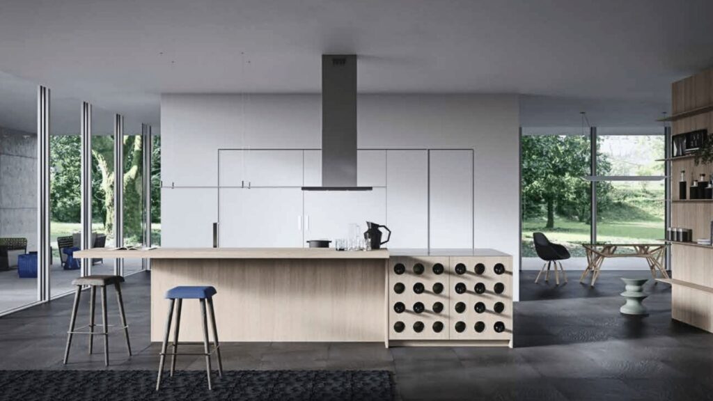 Cocina moderna con isla central en madera clara, vinoteca integrada y mobiliario blanco en espacio abierto con vistas al jardín.